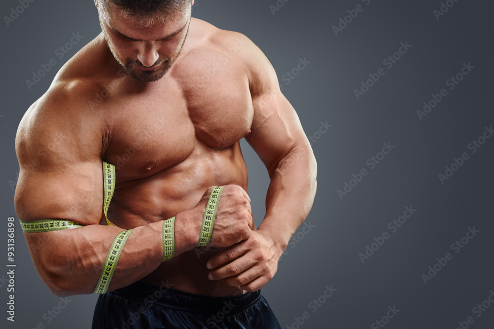 Closeup of bodybuilder holding tape measure. Wrong biceps measuring