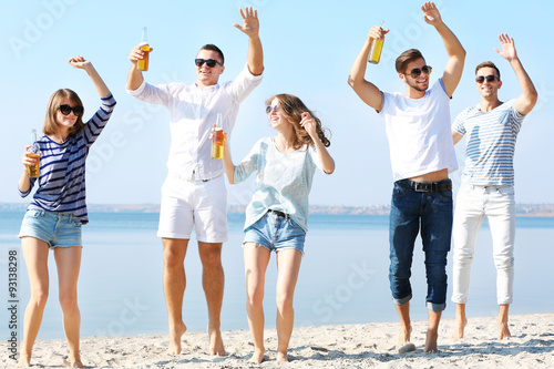 Young people with beer on the riverside