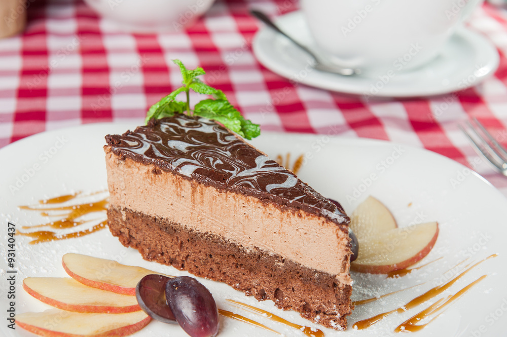 Close up Chocolate Cheesecake with fruits and Green Mint on the white plate on the served restaurant table Close up Chocolate Cheesecake with fruits and Green Mint on the white plate on the served restaurant table