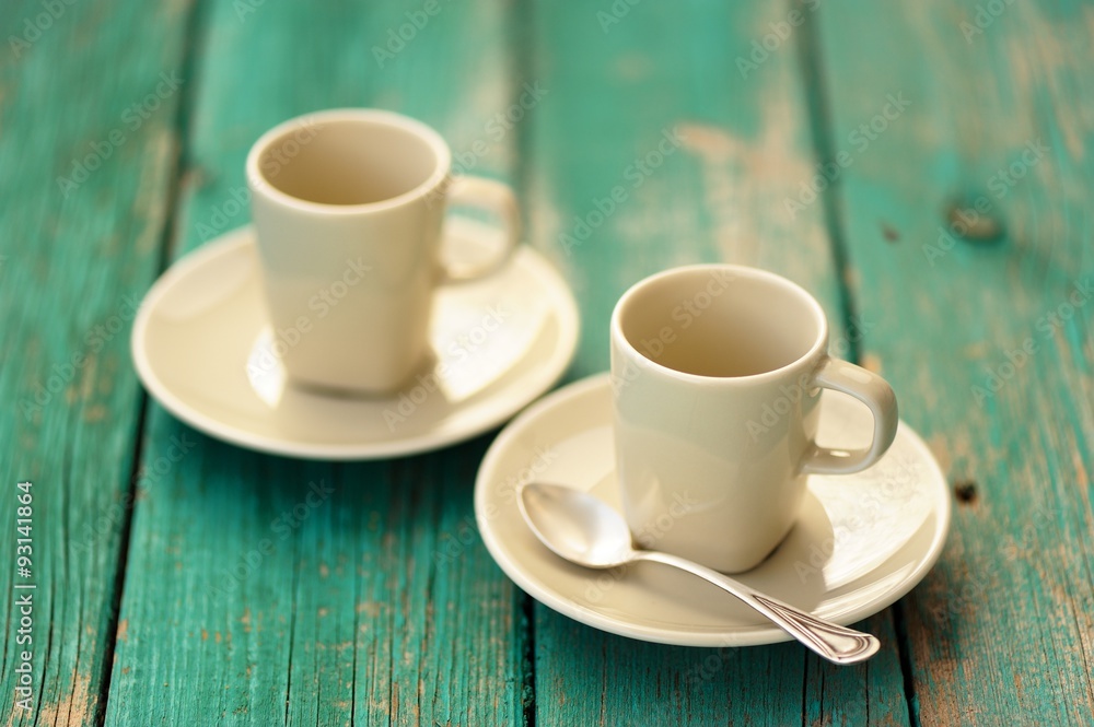 Two empty ebony espresso cups with silver spoon on turquoise sha