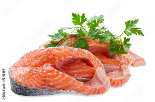 Two pieces of salmon fillet with a sprig of parsley on a white b
