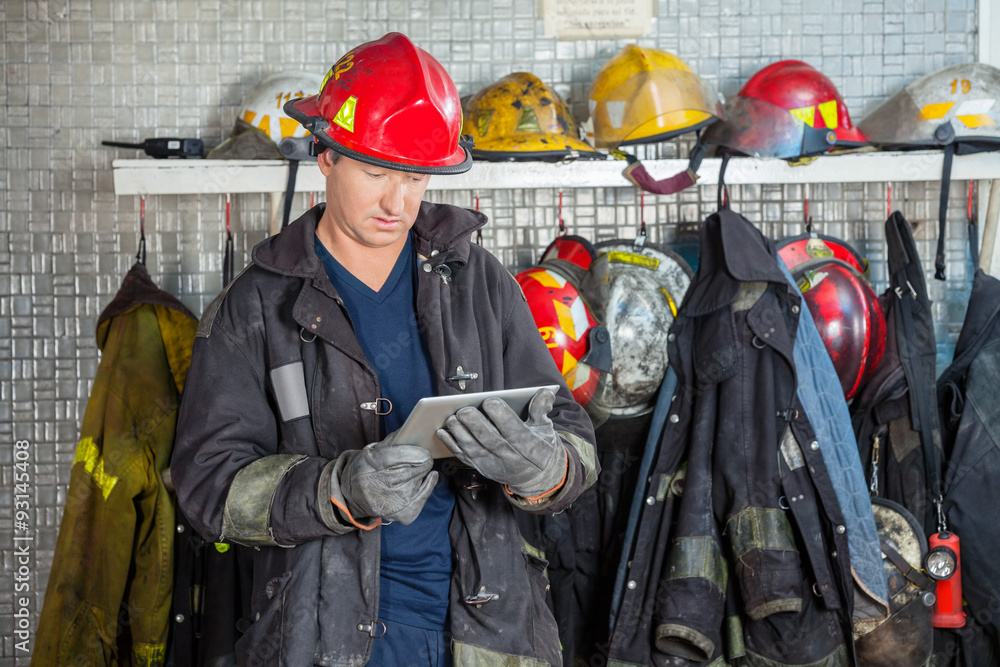 Naklejka premium Fireman Using Digital Tablet At Fire Station