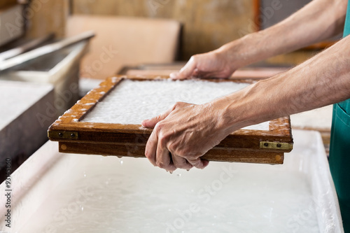 Schilderij op canvas Cropped Image Of Worker Dipping Mold In Pulp And Water