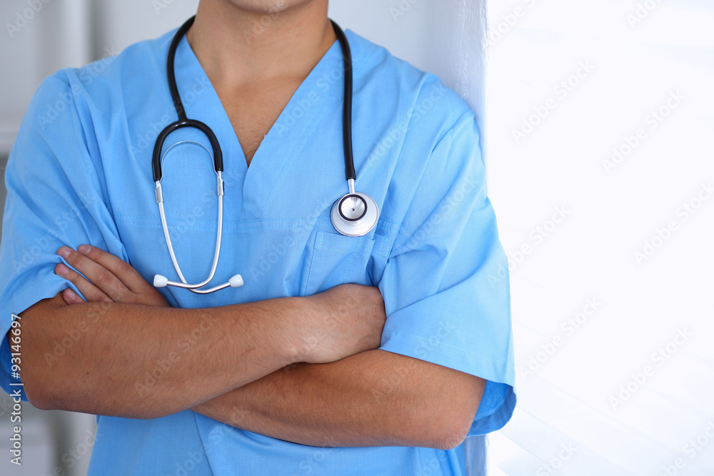 Portrait of unknown male surgeon doctor standing near the wall in hospital office, stethoscope Portrait of unknown male surgeon doctor standing near the wall in hospital office, stethoscope