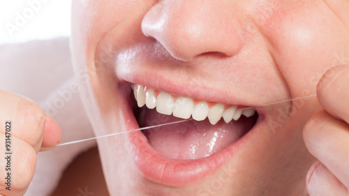 Young man cleaning her white teeth with dental floss