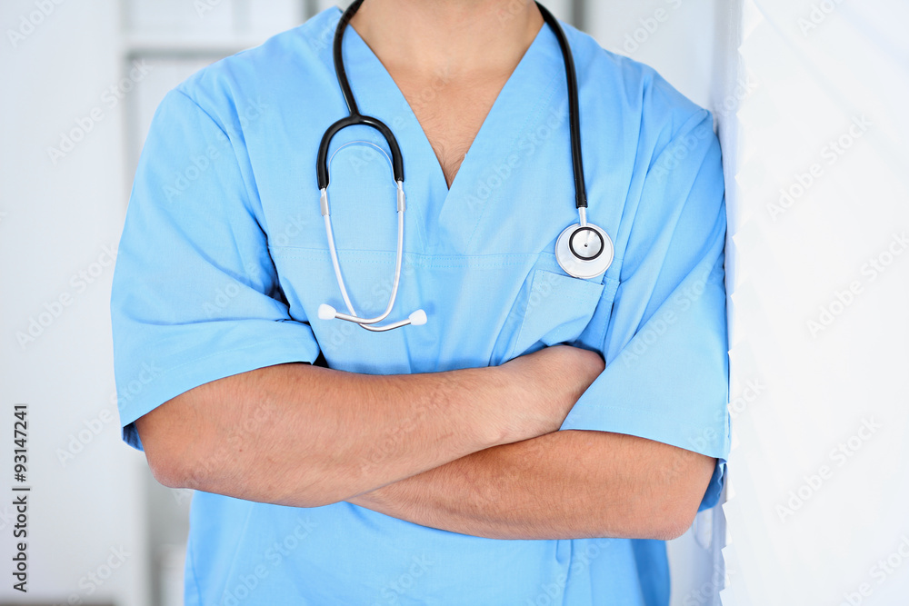 Portrait of unknown male surgeon doctor standing near the wall in hospital office, stethoscope Portrait of unknown male surgeon doctor standing near the wall in hospital office, stethoscope