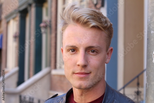 Obraz na plátně Close portrait of handsome adult blonde man, with blured urban classic backgroun