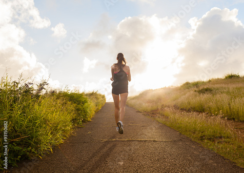 Young woman running on a rural road during sunset