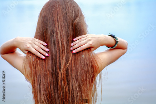 Rear view of long haired brunette posing against sea water on seaside