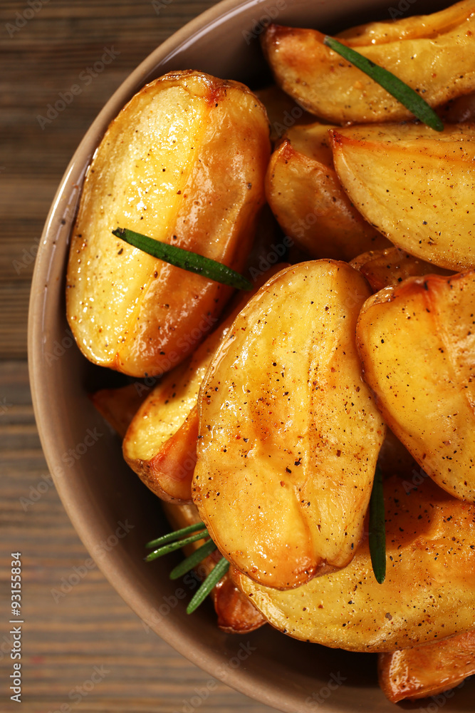 Baked potato wedges on wooden table, closeup Baked potato wedges on wooden table, closeup