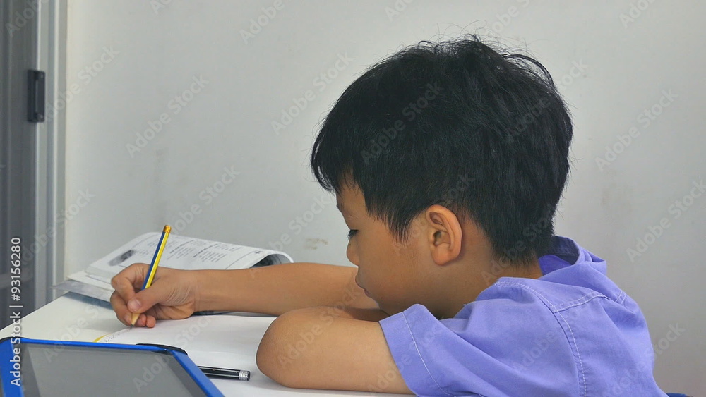 Little Asian child feel sleepy between doing homework Little Asian child feel sleepy between doing homework