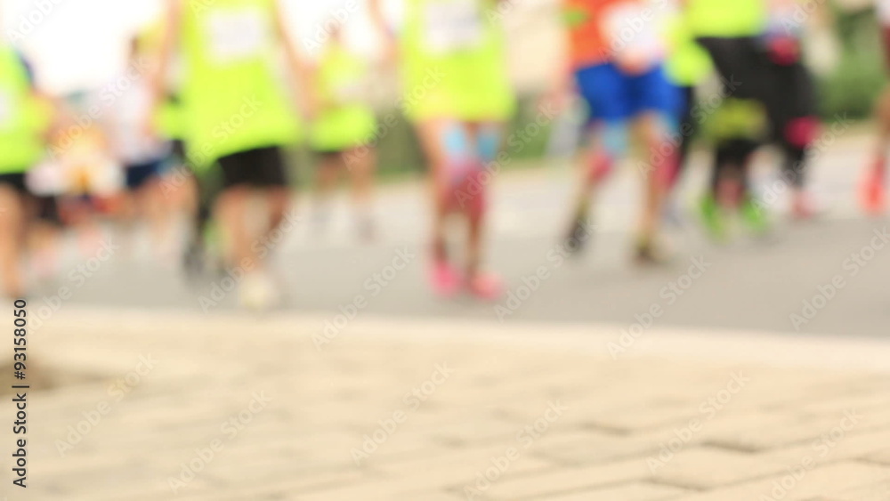 defocused marathon runners running on city road defocused marathon runners running on city road