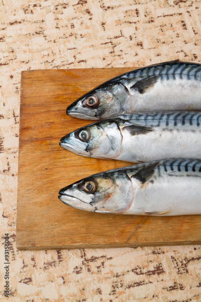 Three mackerel on a Board on the table.