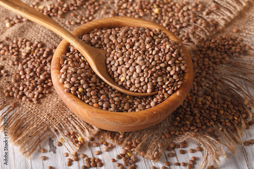 Dry brown lentils in a wooden bowl close-up. Horizontal, rustic
 photo