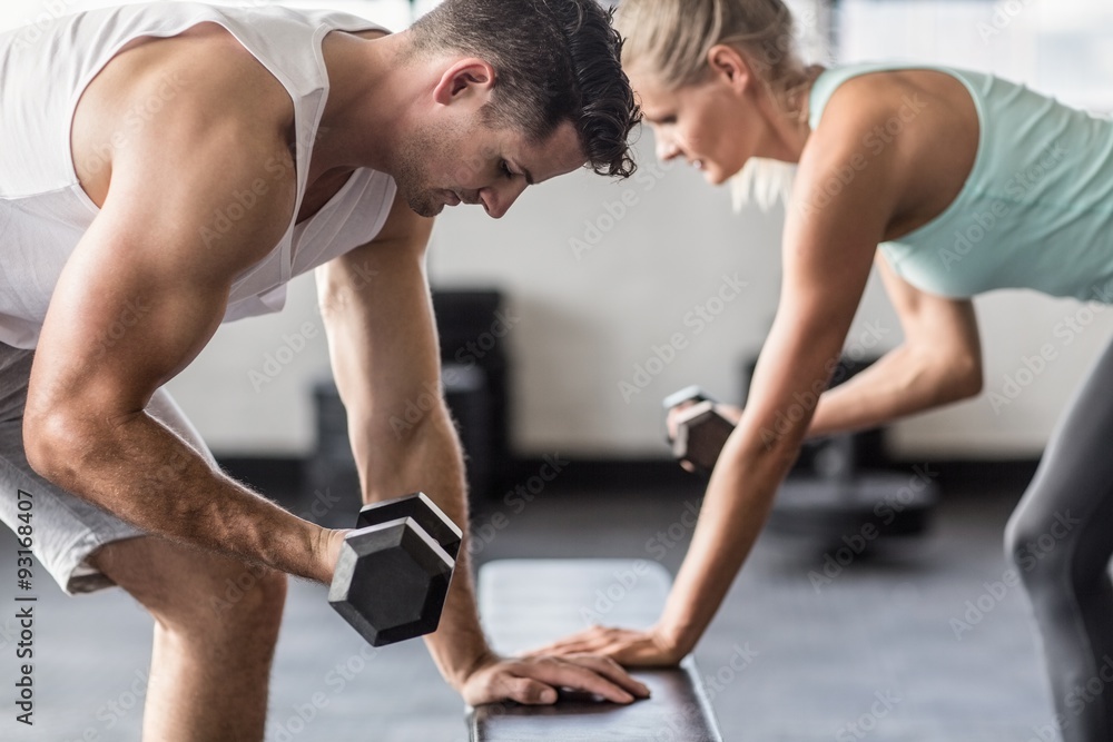 couple exercising with dumbells on a workout bench couple exercising with dumbells on a workout bench