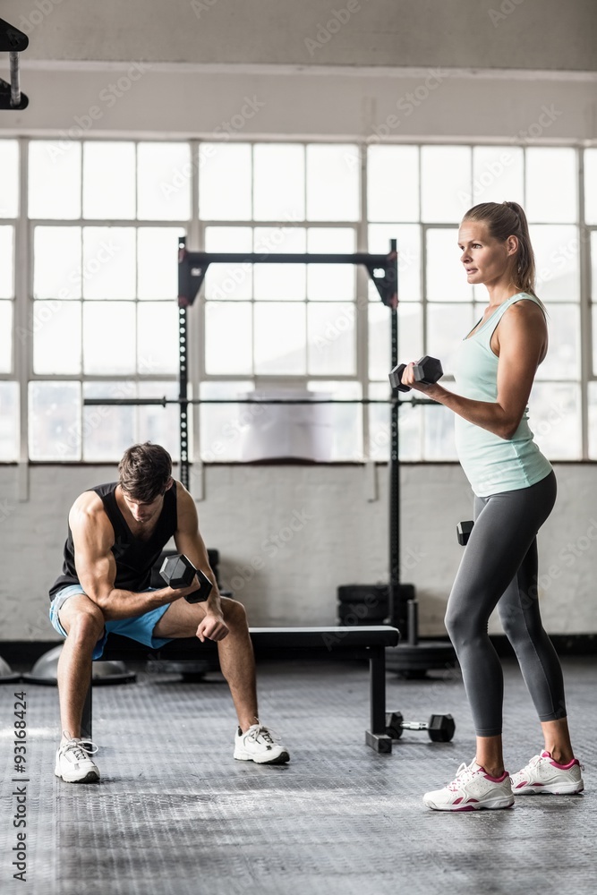 Sporty couple exercising with dumbbells Sporty couple exercising with dumbbells