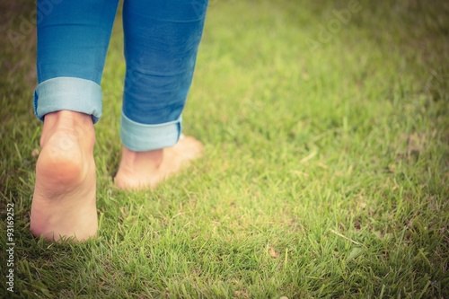 Low section of woman walking on grassy landscape 