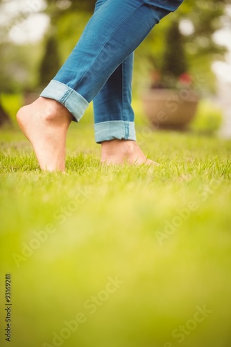 Low section of woman walking on green grass 