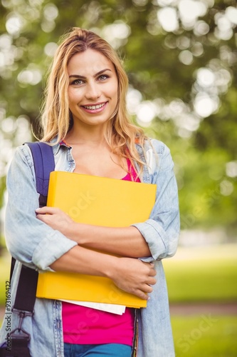 Portrait of smiling female student carrying bag and file 