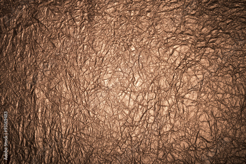 Close up of wrinkled textured metallic bronze grunge background with dark vignette shadowing