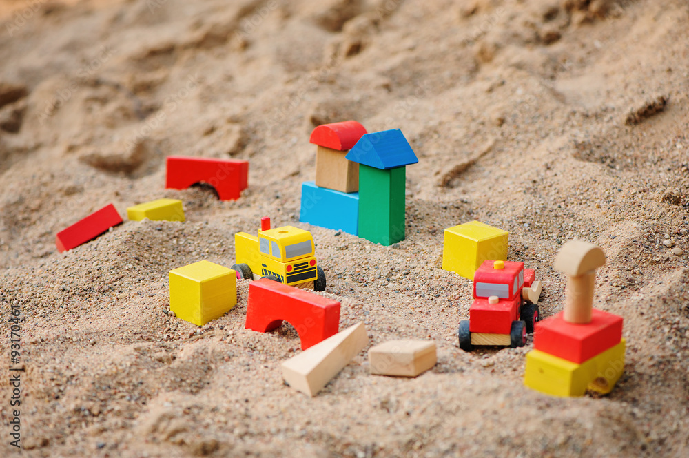 toy houses and trucks made of colorful wooden bricks in sandbox toy houses and trucks made of colorful wooden bricks in sandbox