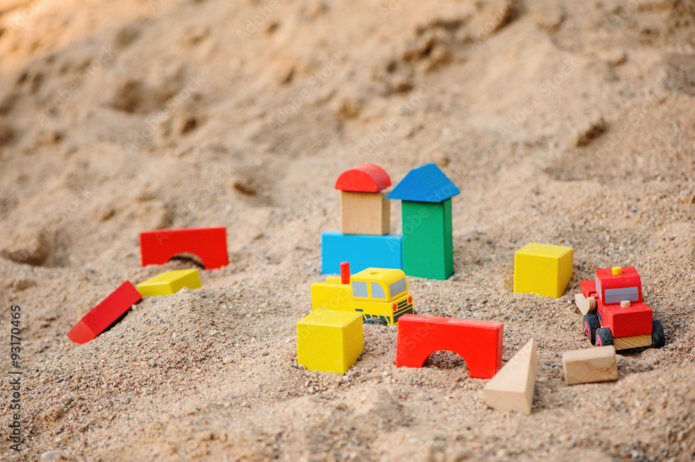 toy houses and trucks made of colorful wooden bricks in sandbox toy houses and trucks made of colorful wooden bricks in sandbox
