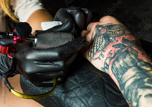 Tattooist makes a tattoo on client's arm © belyjmishka