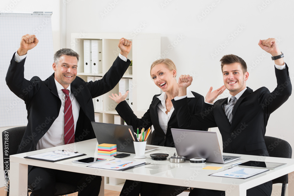 Happy Businesspeople With Arm Raised In Office Happy Businesspeople With Arm Raised In Office