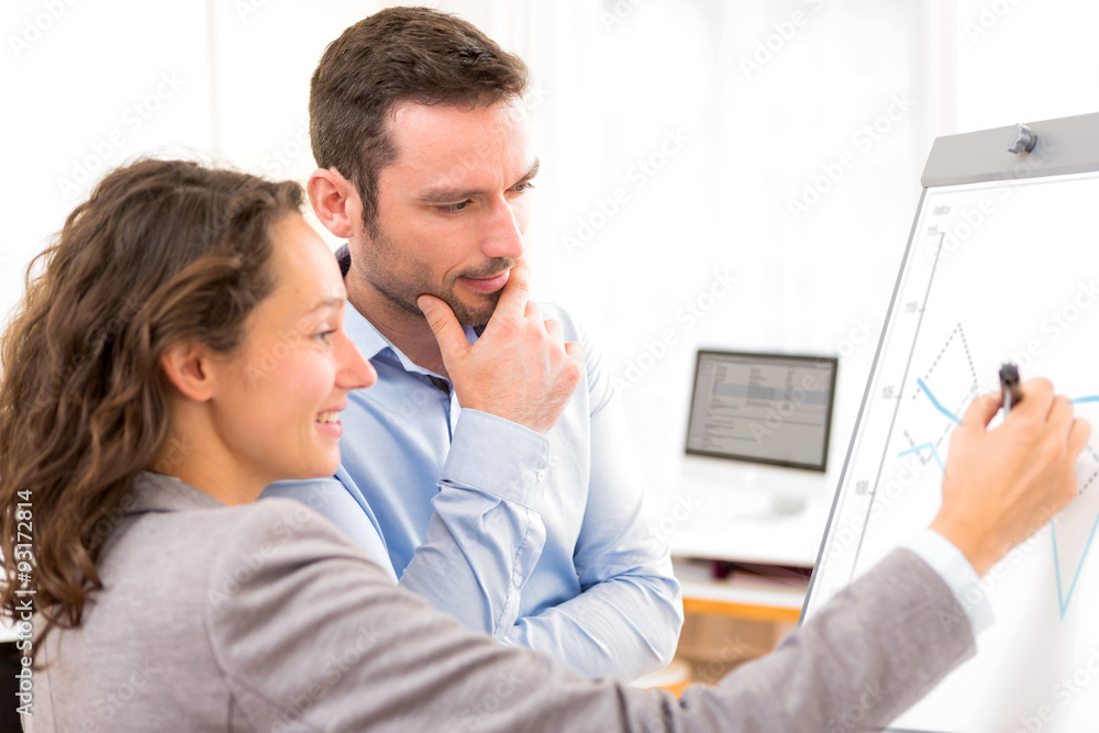 Business man and woman, analysing stats on a paperboard Business man and woman, analysing stats on a paperboard