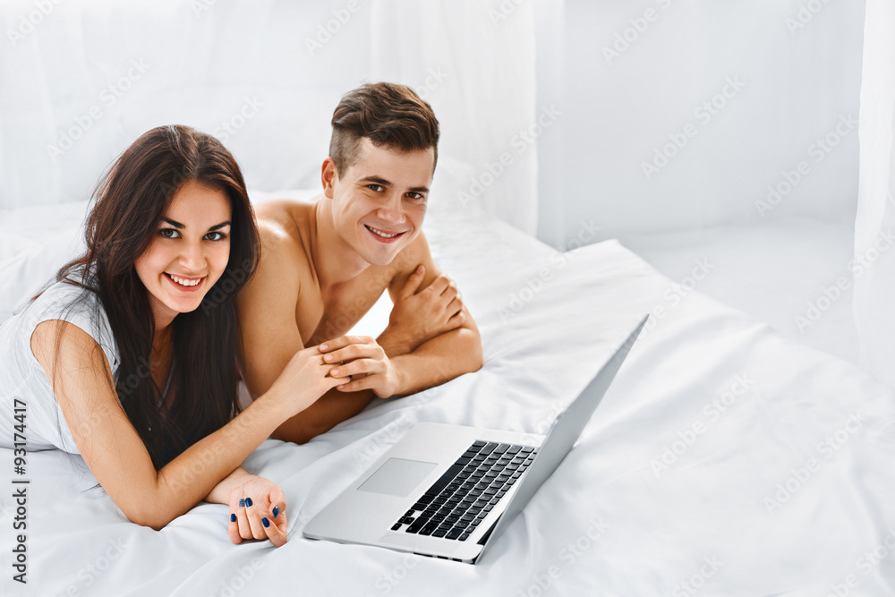Couple with laptop on bed