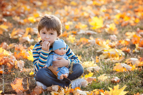 Cute boy, sitting on lawn, autumn day, eating pancakes