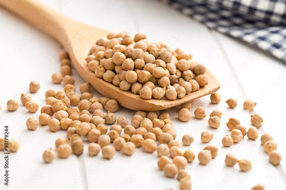 uncooked chickpeas on wooden spoon uncooked chickpeas on wooden spoon