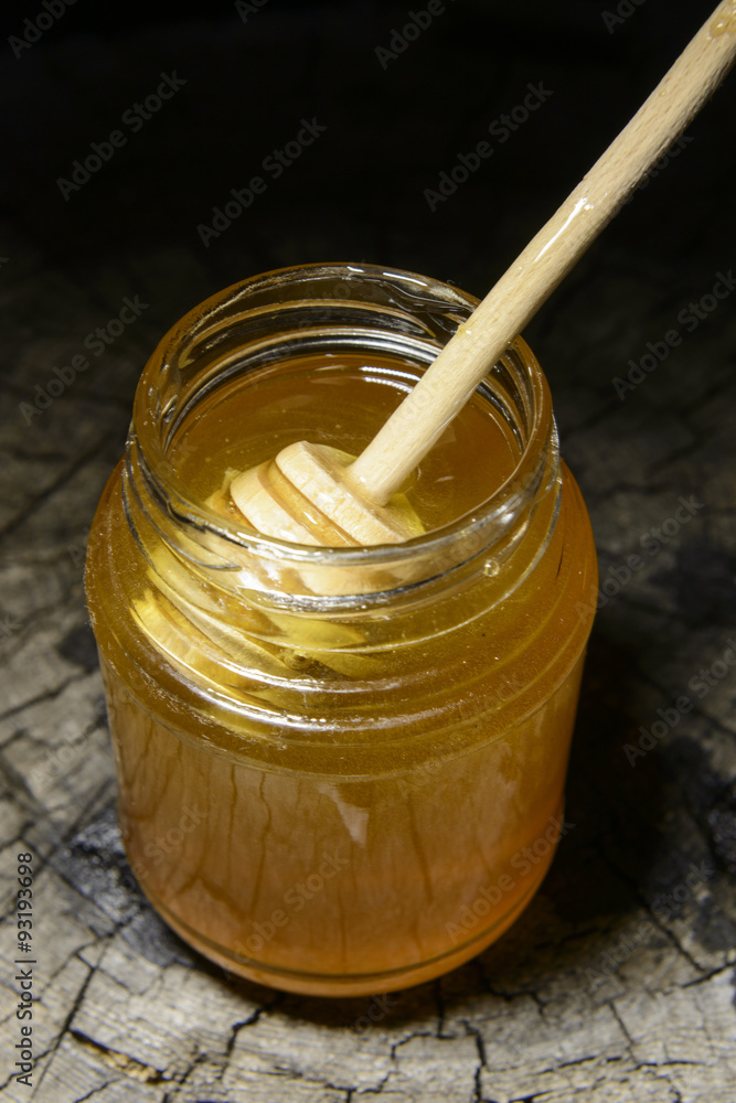 jar of honey and stick to honey on a wooden background jar of honey and stick to honey on a wooden background