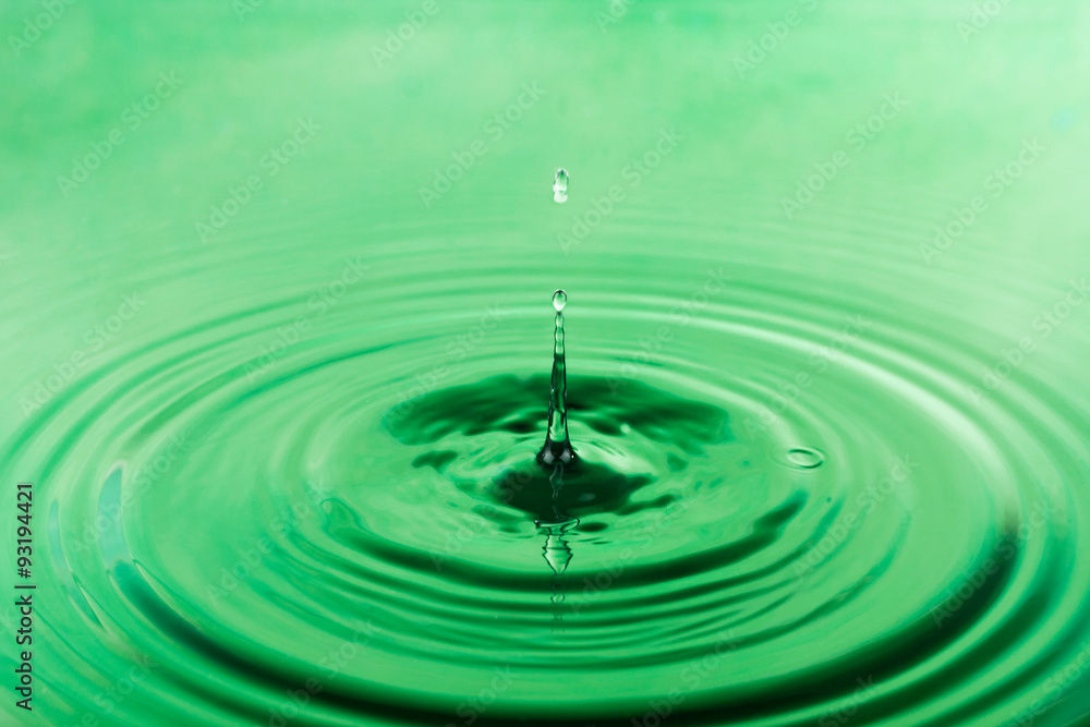 Drop of water falling into the green water
