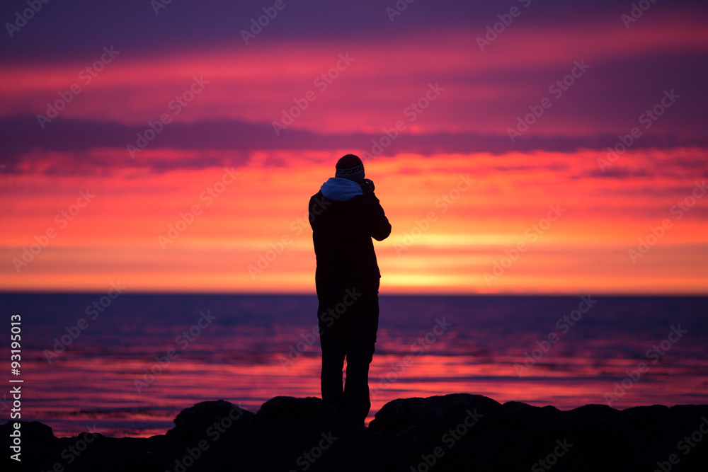 silhouetted photographer on Icelandic coast during sunset