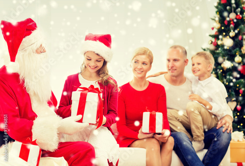 smiling family with santa claus and gifts at home
