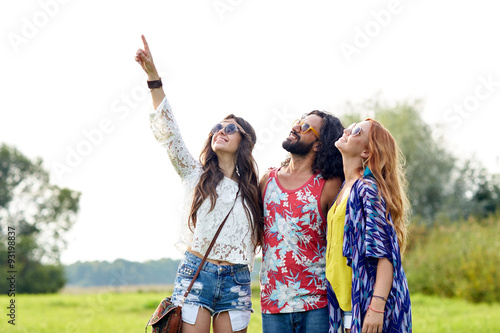 happy hippie friends pointing finger outdoors