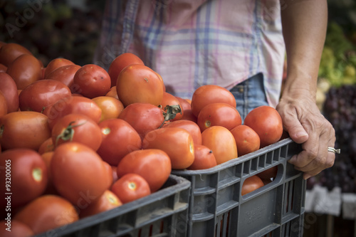 Mexico, Nayarit, Bucerias, woman with box of tomatoes at local farm produce market photo