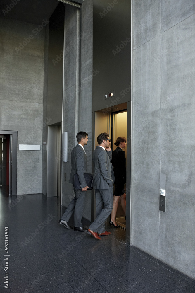 Group of businesspeople entering the elevator in office Group of businesspeople entering the elevator in office