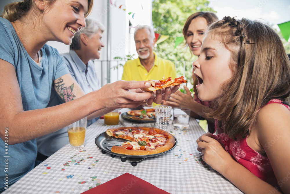 Girl being fed with homemade pizza at family party Girl being fed with homemade pizza at family party