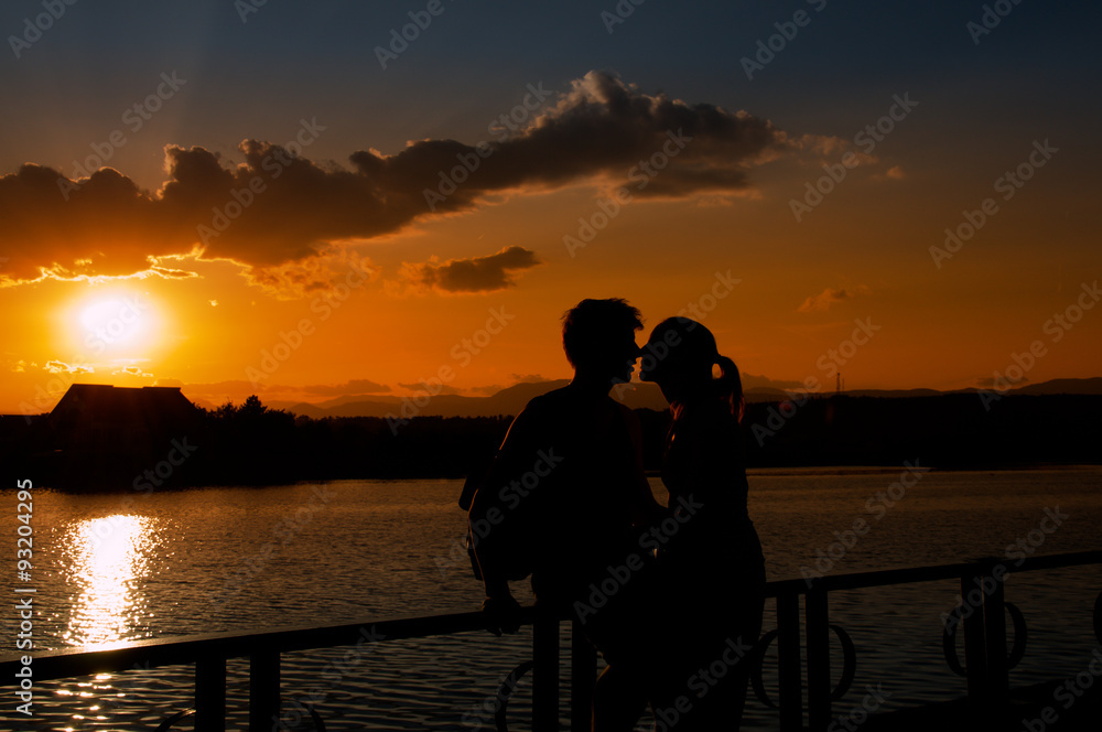 Young couple silhouettes kissing at sunset