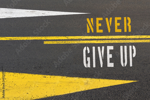 Never Give Up written on asphalt road.
