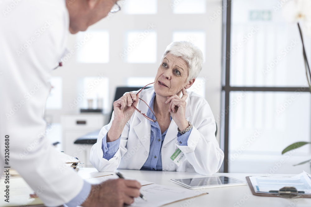 Two doctors talking at desk Two doctors talking at desk