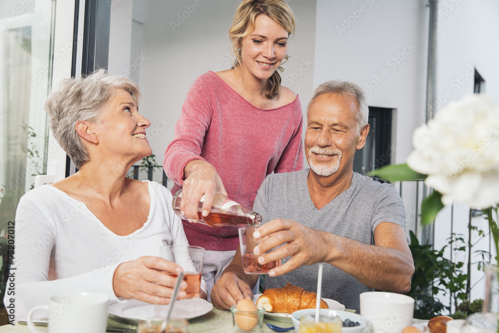 Adult daughter having breakfast with her parents on balcony Adult daughter having breakfast with her parents on balcony
