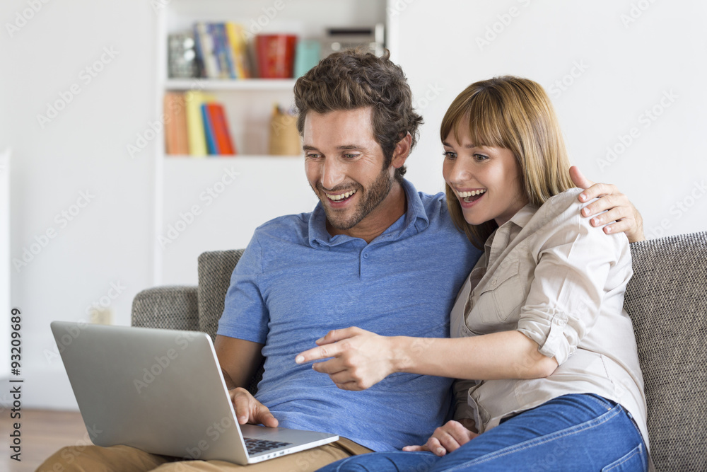Happy successful young couple with laptop on sofa in modern apartment Happy successful young couple with laptop on sofa in modern apartment