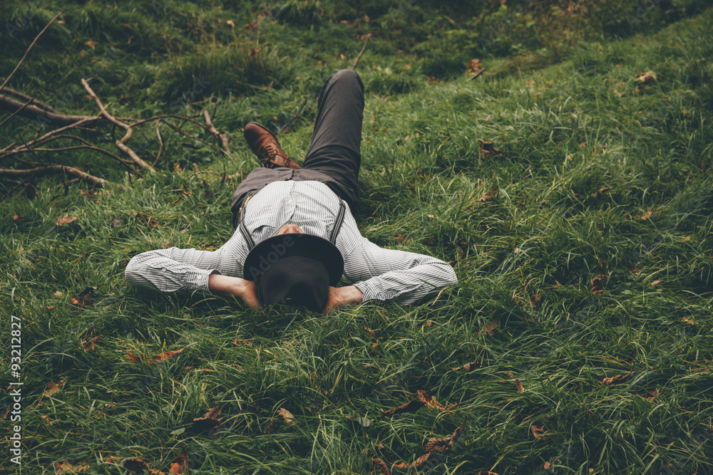 Young man lying on a meadow with hands behind his head Young man lying on a meadow with hands behind his head