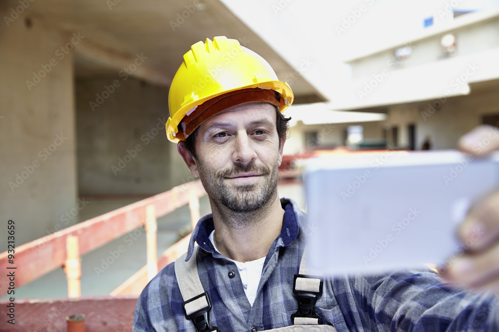 Smiling man with hard hat on construction site taking a selfie Smiling man with hard hat on construction site taking a selfie