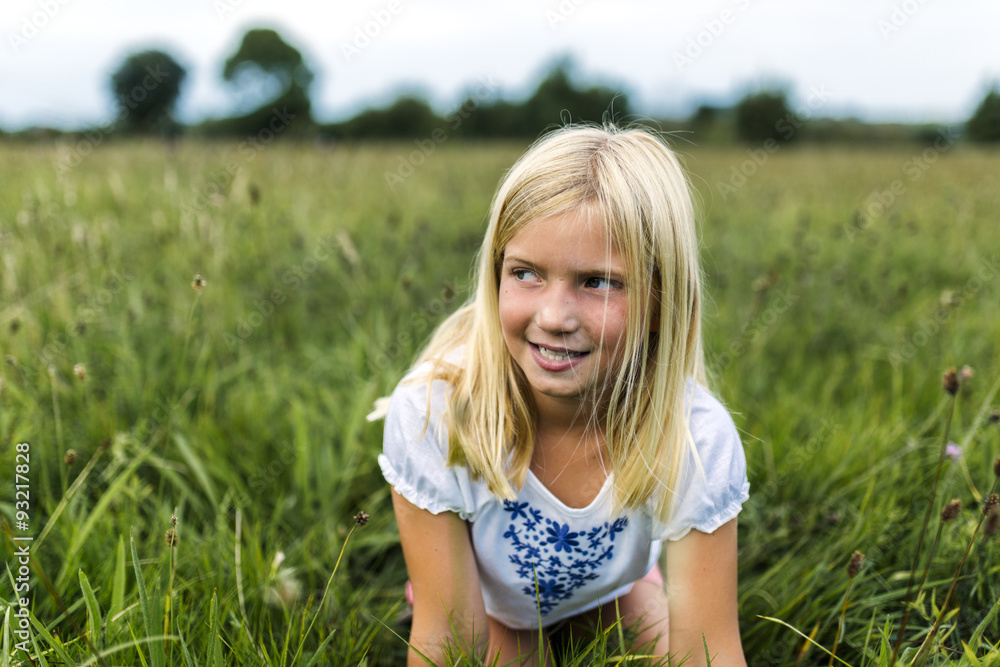 Portrait of girl kneeling on a meadow watching something Portrait of girl kneeling on a meadow watching something