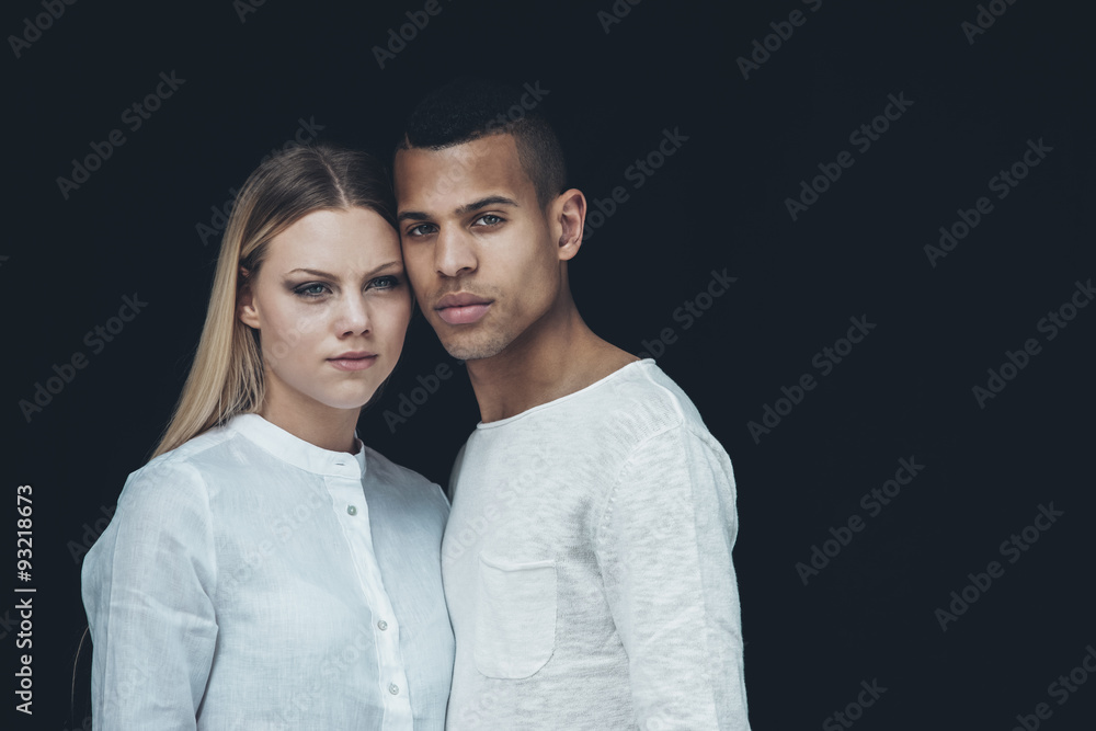 Portrait of young couple wearing white clothes head to head in front of black background Portrait of young couple wearing white clothes head to head in front of black background