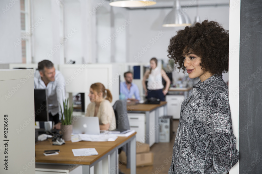 Smiling woman in office with colleagues in background Smiling woman in office with colleagues in background